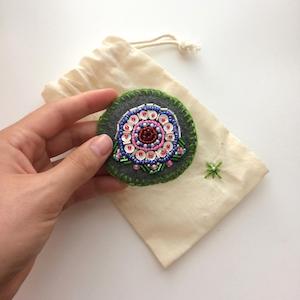 Magnolia flower embroidered onto gray felt with sequins and glass beads.