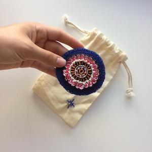 Pink cactus flower embroidered onto blue felt with sequins, pearls and glass beads.