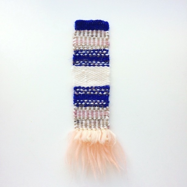 Narrow, rectangular weaving featuring verticle stripes, horizontal dashed lines and fringe resembling layered feathers. In cobalt, blush, lilac, brown and white.