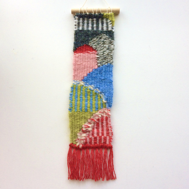 Narrow, rectangular weaving, resembling a hilly countryside. In red, pink, chartreuse, blue, gray and white.