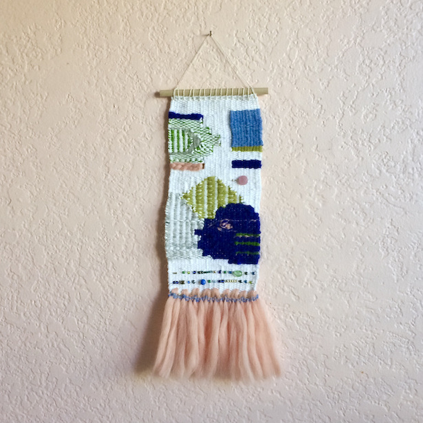 Rectangular weaving with geometric and chinoiserie-inspired shapes, beading, and fringe resembling a tutu. In blush, cobalt, greens, medium blue, white and gray.